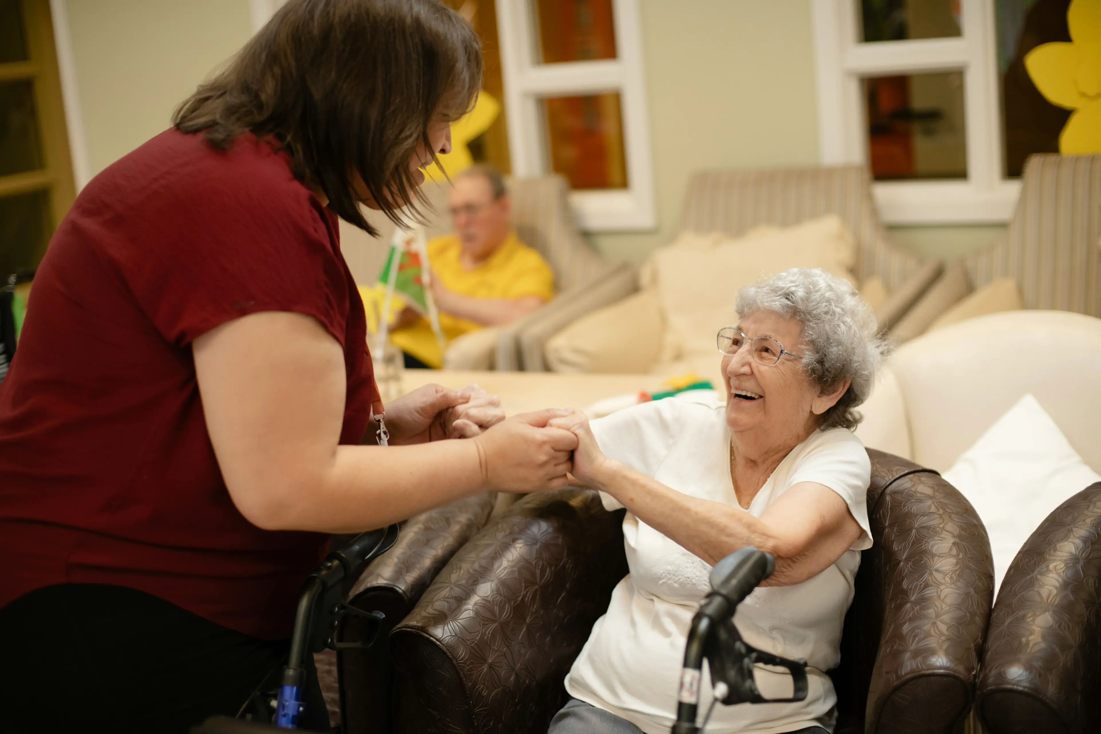 An aged-care worker supporting an older woman in a relaxed home setting